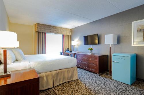 a hotel room with a bed and a television at Old Stone Inn Boutique Hotel in Niagara Falls