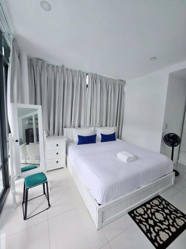 a white bedroom with a large bed and a mirror at Calm Tao Pool Villa in Koh Tao