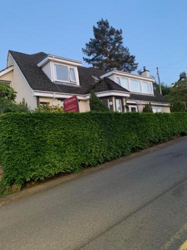 a house with a hedge in front of a street at Stobahn Guest House in Fort William