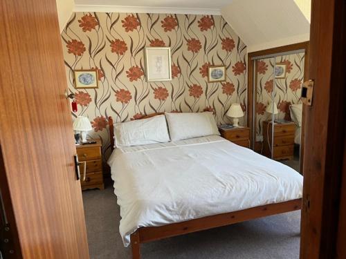 a bedroom with a bed and a wall with flowers at Stobahn Guest House in Fort William