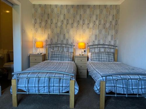two beds in a room with two lamps on both sides at Stobahn Guest House in Fort William