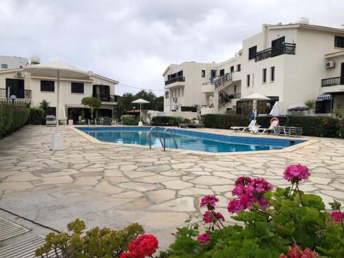 a resort with a swimming pool and some pink flowers at Luxurious 3-Bed Villa, Modern Decor, Communal Pool in Paphos