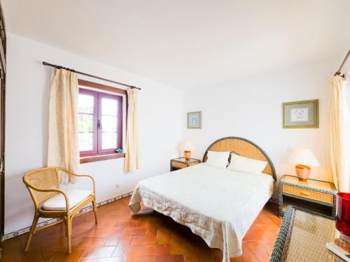 een slaapkamer met een bed, een stoel en een raam bij Villa Dunn Mar V3 by YHA in Cabanas de Tavira