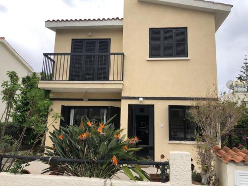 a house with a balcony and a plant at Luxurious 3-Bed Villa, Modern Decor, Communal Pool in Paphos