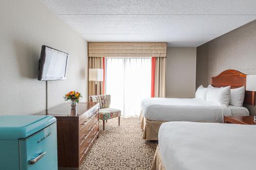 a hotel room with two beds and a television at Old Stone Inn Boutique Hotel in Niagara Falls