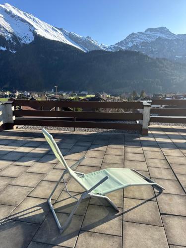 a green chair sitting on a patio with snow covered mountains at Ferienwohnung Engelberg in Engelberg