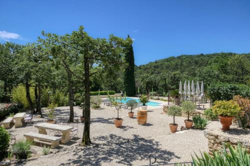 un jardin avec des bancs et des arbres ainsi qu'une piscine dans l'établissement Le Hameau Fleur de Pierres , Chambre , Gite et Table d'Hôtes, à Murs