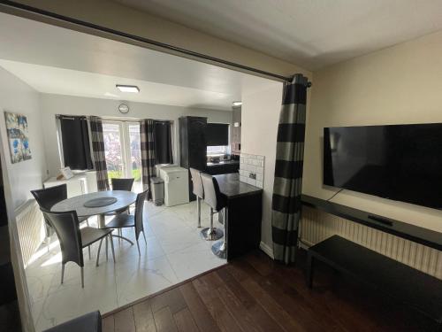 a living room with a dining table and a flat screen tv at Garden Apartment nr Heathrow Airport & Elizabeth Line Train Station with Parking for 2 cars in Hayes