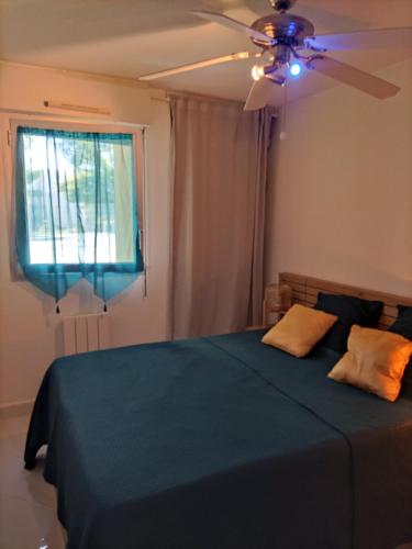 une chambre avec un lit bleu avec un ventilateur de plafond dans l'établissement T2 Plage la corniche, les Tennis de castelmare à Sète appartement classé 3 etoiles, à Sète
