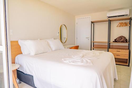 a bedroom with a white bed and a mirror at Qavi - Flat Vista Mar de Pirangi #Living14 in Pirangi do Norte