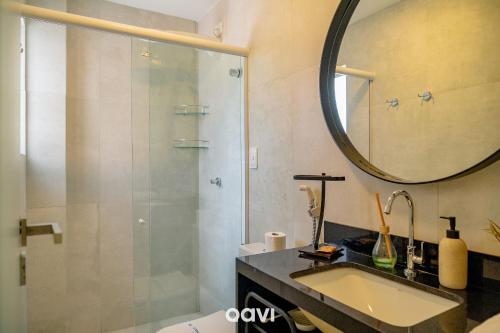a bathroom with a shower and a sink and a mirror at Qavi - Flat Vista Mar de Pirangi #Living14 in Pirangi do Norte