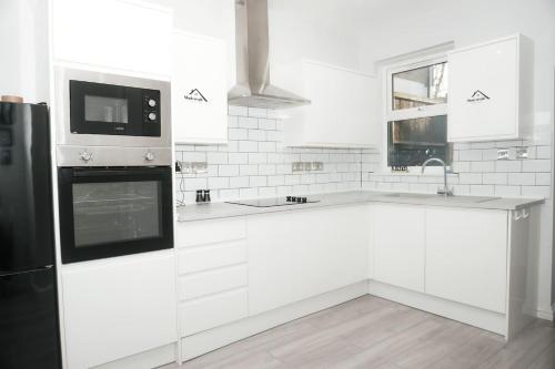 a white kitchen with a sink and a microwave at Luxury 3-Bedroom Home , with Free parking in Dartford