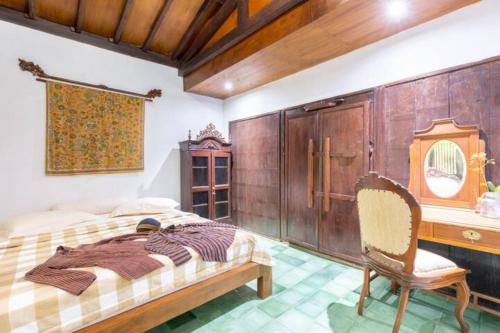 une chambre avec un lit, un bureau et une chaise dans l'établissement Vintage room 2 in Joglo House By penggemarlawas, à Kamparganya