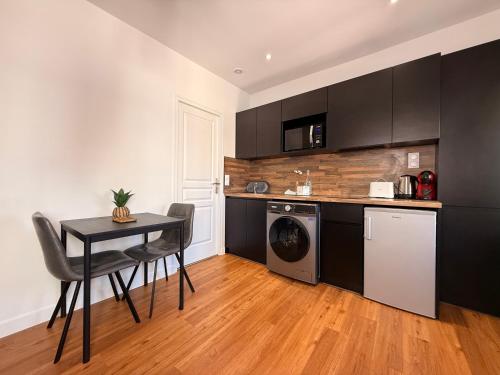 une cuisine avec des armoires noires et une table avec des chaises dans l'établissement Le Saint Just T2 proche des Halles Wifi, à Narbonne