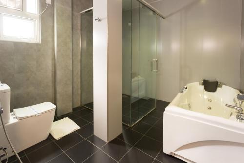 a bathroom with a tub and a sink and a toilet at Hotel Grand Turf By GSP in Nuwara Eliya