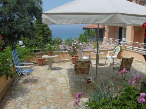 a patio with a table and chairs and an umbrella at Tonia Apartments Kontogialos in Pelekas