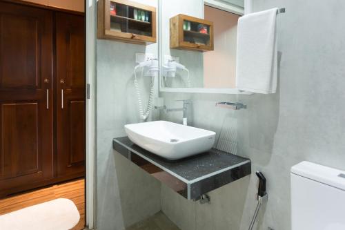 a bathroom with a white sink and a mirror at Hotel Grand Turf By GSP in Nuwara Eliya
