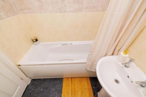 a bathroom with a tub and a toilet and a sink at House Carlisle in Great Oakley