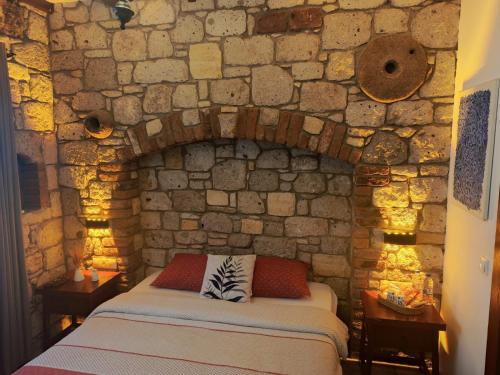 a bedroom with a bed in a stone wall at KEYİFTE Alaçatı in Alacati