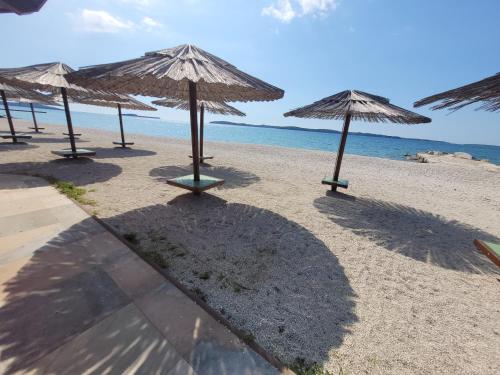 a group of straw umbrellas on the beach at Ferienwohnung Istrien 200m Strand in Fažana