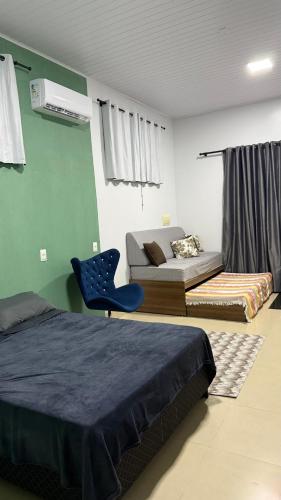 a bedroom with two beds and a blue chair at Nalevaiko - Kitnet Moderna e Funcional in Sinop