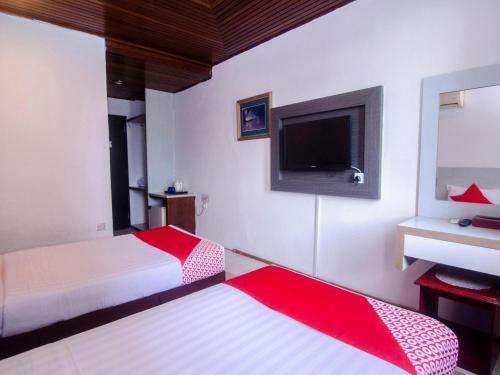 a bedroom with two beds and a flat screen tv at Hotel O Mayfair Hotel in Kuching