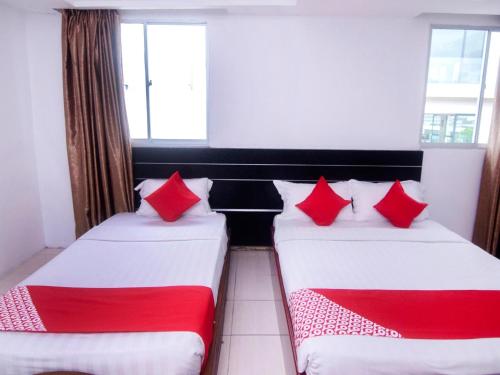 two beds in a room with red and white pillows at Hotel O Mayfair Hotel in Kuching