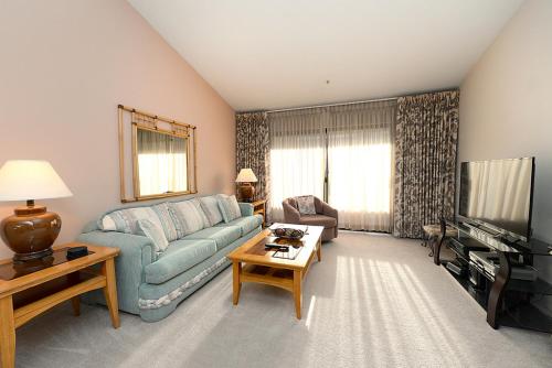 a living room with a blue couch and a tv at Plaza Villas Getaway - 1br Downtown PS in Palm Springs