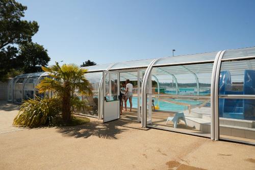 - un bâtiment en verre avec une piscine et des personnes dans l'établissement Camping Au Soir D'été, à Mesquer