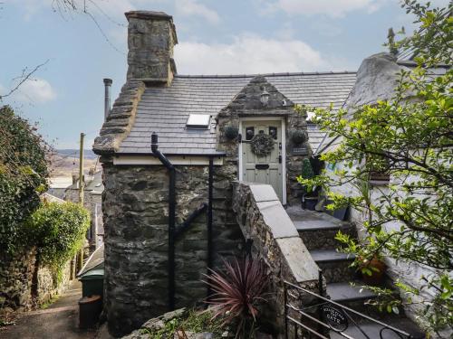 a stone cottage with a white door and stairs at Top Cottage Barmouth in Barmouth