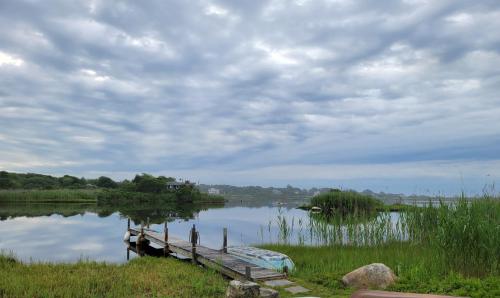a dock on a lake with a cloudy sky at Waterfront Salt Pond House, water view and dock in Charlestown