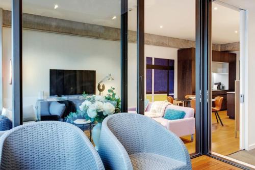 a living room with blue chairs and a tv at Premium Cityscape Abode w Skytower view & Parking in Auckland
