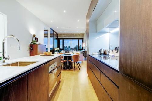 a large kitchen with a sink and a table at Premium Cityscape Abode w Skytower view & Parking in Auckland