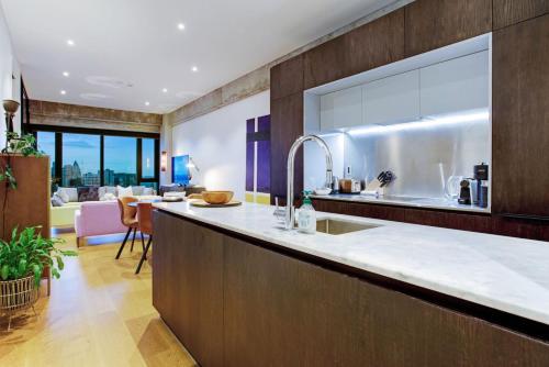 a kitchen with a sink and a living room at Premium Cityscape Abode w Skytower view & Parking in Auckland