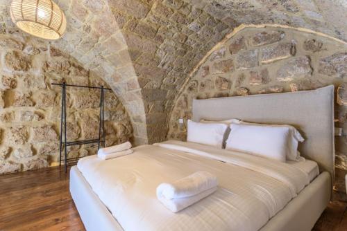 a bed in a room with a stone wall at Arcades 1 de Bahsa in Batroûn