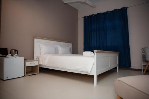 a bedroom with a white bed with a blue curtain at Landmark in Quatre Bornes