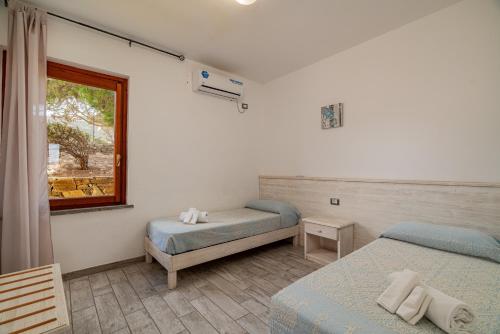 a bedroom with two beds and a window at Club Esse Sporting in Stintino