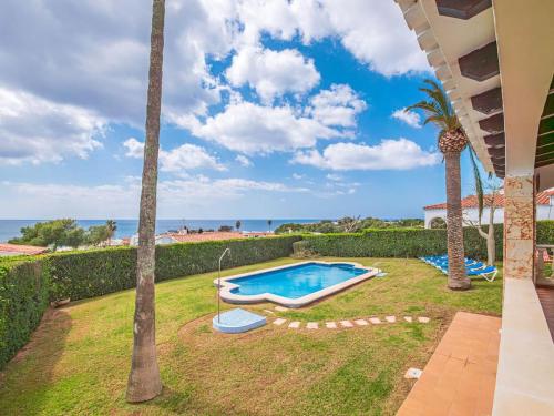 un patio trasero con piscina y palmeras en Villa Sur, en Binisafua