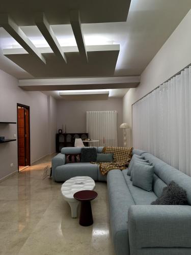 a living room with two blue couches and a table at Maze 3BR Sin El Fil in Sinn al Fīl