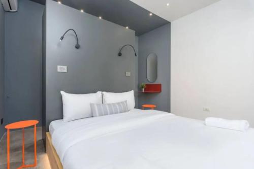 a bedroom with a large white bed and two orange chairs at The Club 1BR in Gemmayze in Al Mudawwar