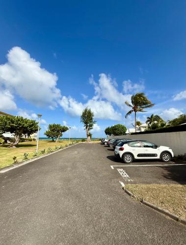 a row of cars parked in a parking lot at T2 vue mer avec accès direct lagon et 5 min plage in Sainte-Anne