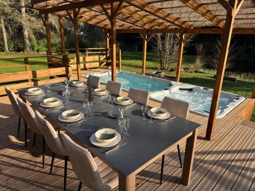 a table and chairs on a deck with a swimming pool at L'écrin de la forêt in Jeanménil