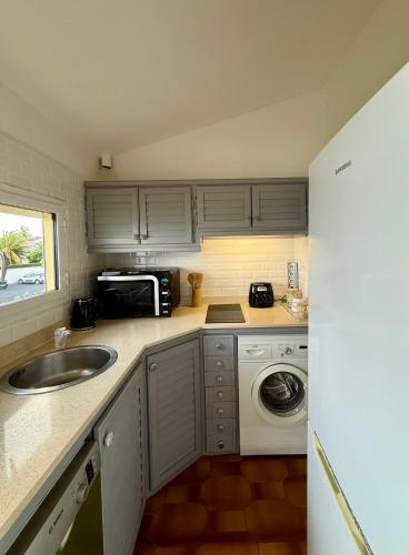 a small kitchen with a sink and a microwave at T2 vue mer avec accès direct lagon et 5 min plage in Sainte-Anne