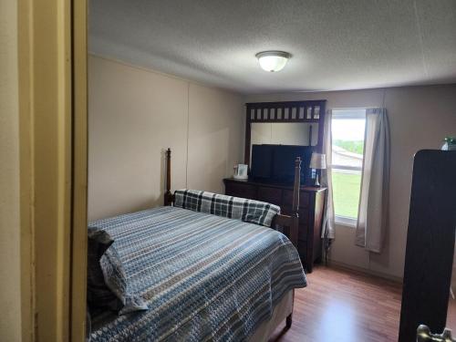 a bedroom with a bed and a television and a window at Pop's Place -Lakeview 3bd 2 ba on 6 acres in Fort Gibson