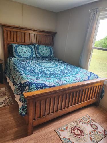 a bedroom with a bed with a wooden frame and a window at Pop's Place -Lakeview 3bd 2 ba on 6 acres in Fort Gibson