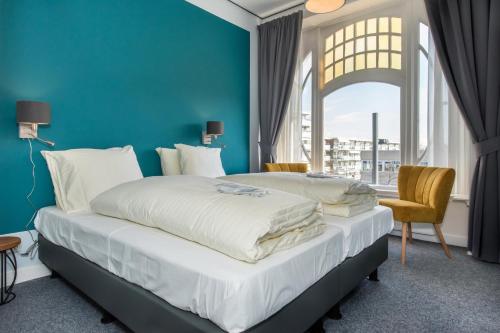 2 camas en una habitación con una pared azul en Villahotel Vlissingen, en Vlissingen