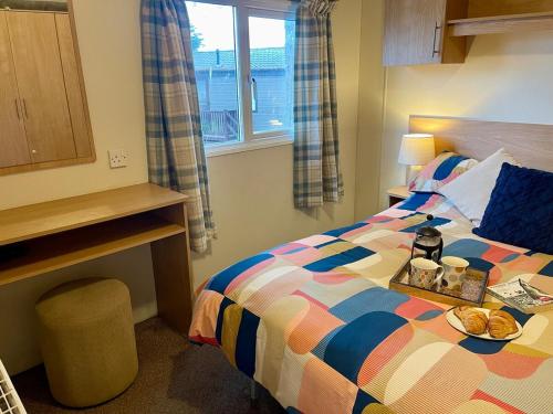 a bedroom with a bed with a tray of food on it at Seascape at Landscove Holiday Park, Brixham in Brixham