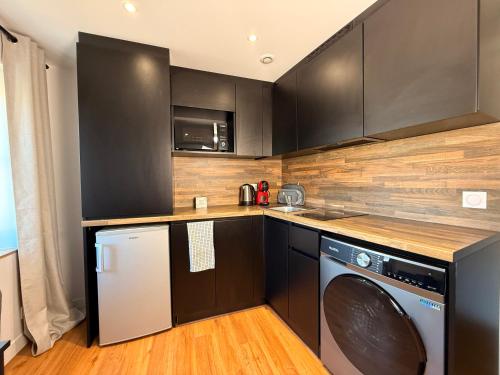 une cuisine avec des armoires noires et un lave-linge/sèche-linge dans l'établissement Le Baroque Studio Wifi, à Narbonne