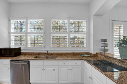 a kitchen with white cabinets and a sink and windows at Martinique Vitamin Sea 10C in Gulf Highlands
