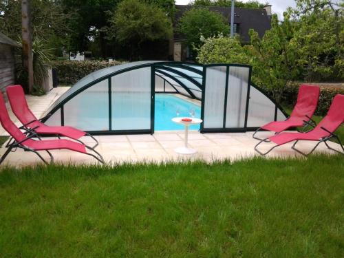 - deux chaises et une table dans l'herbe à côté de la piscine dans l'établissement Tremoyec, à Surzur